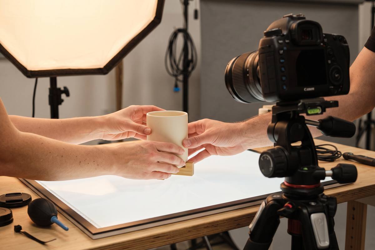 Hands arranging a product in front of a camera on a tripod